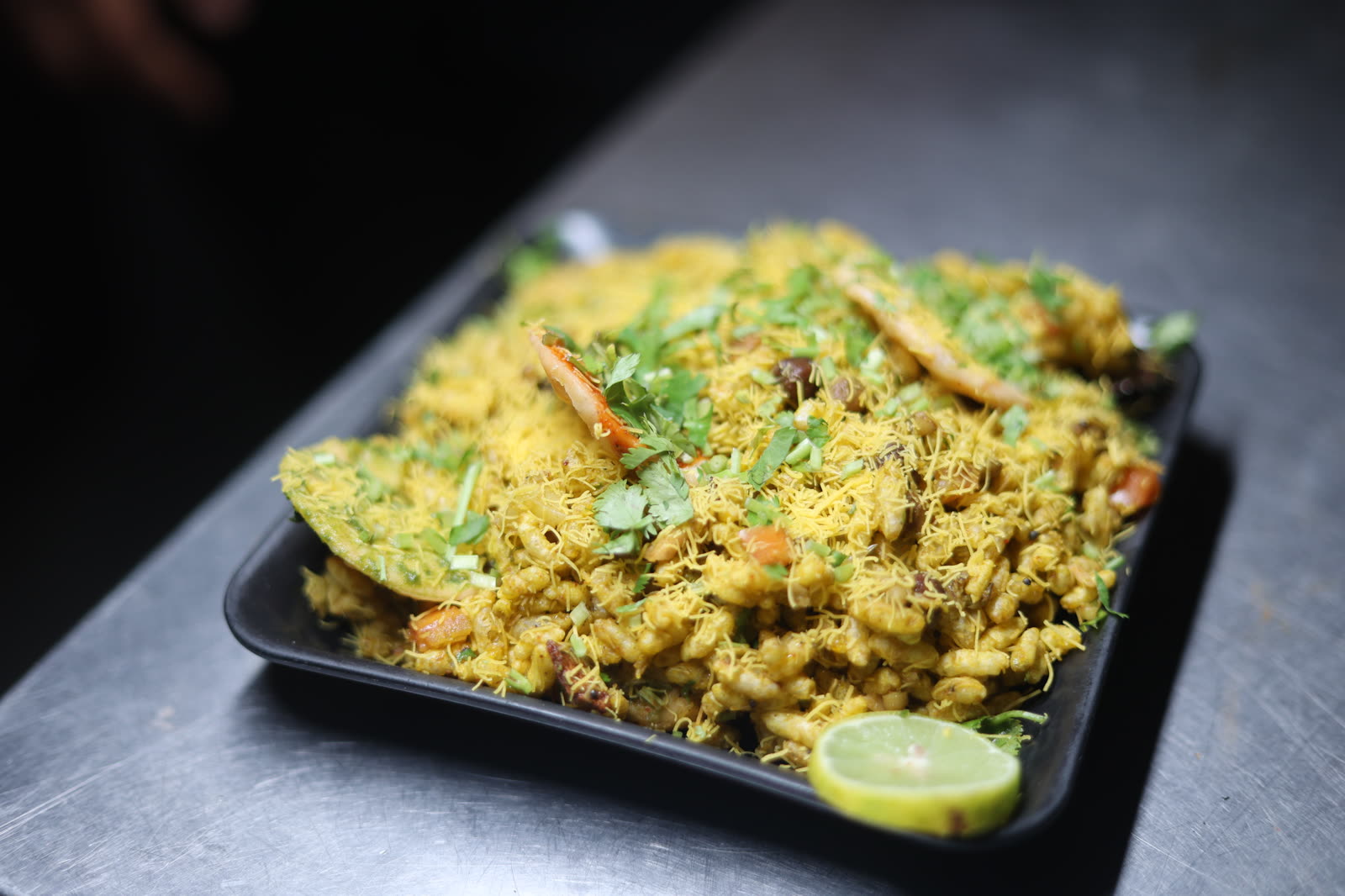 Bhel Puri topped with sev, herbs and lime