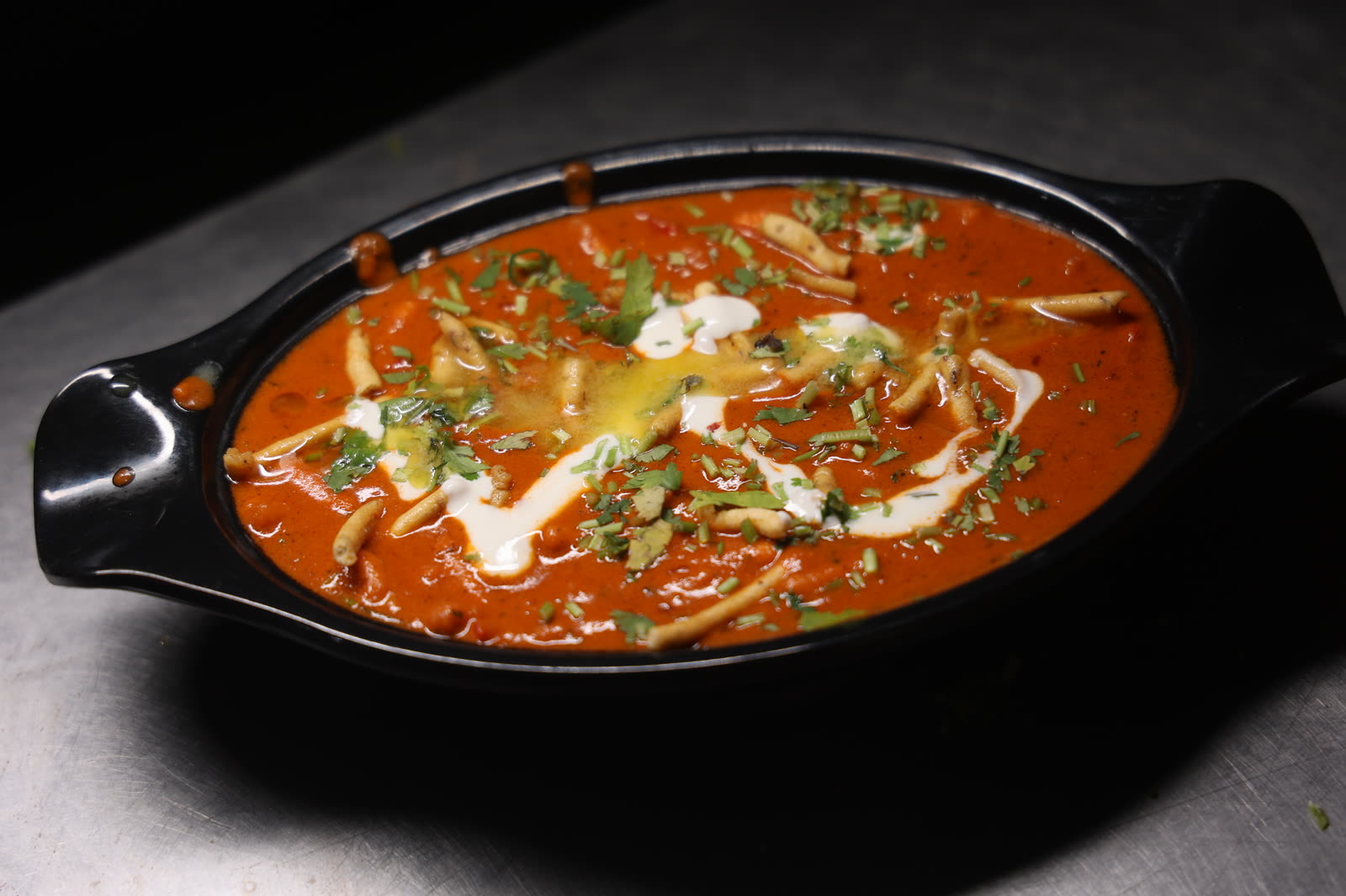 Sev Tamatar curry garnished with sev and cream